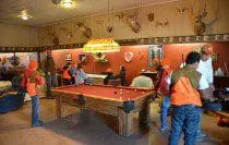 People playing pool in a rustic room.
