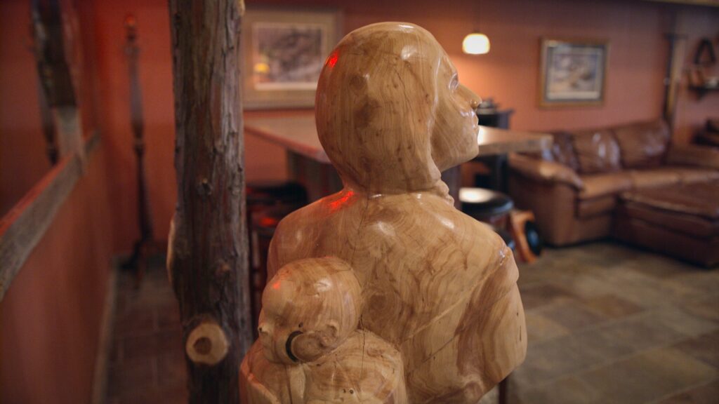 Photo of Native American wood art showing a mother with baby on her back at Ringnecks Lodge.
